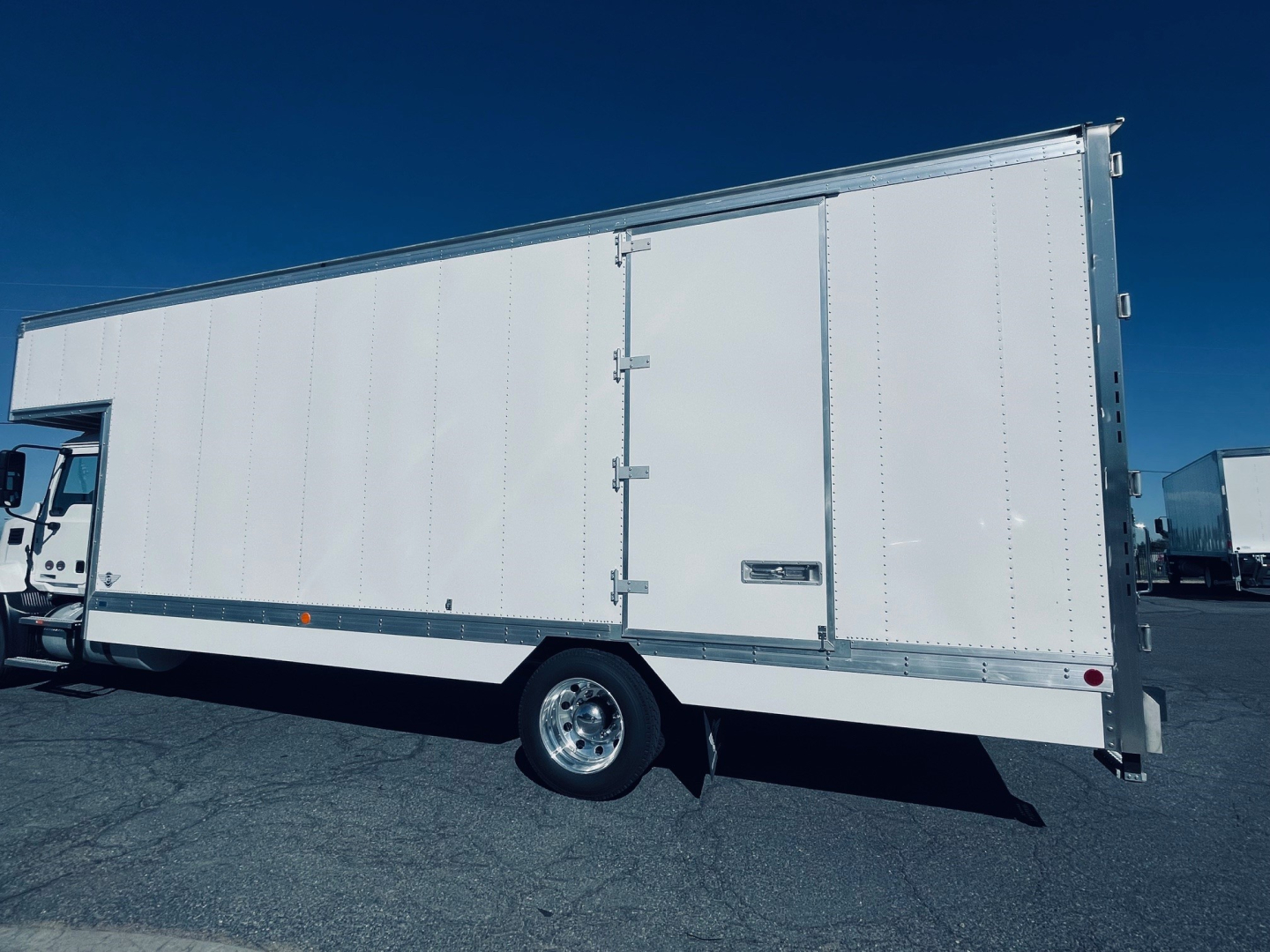 Box truck side view with steel cargo box and rear doors, white exterior, single rear wheel, no visible branding.