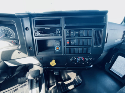 Dashboard of a 2026 Mack MD6 showing instrument cluster, radio, climate controls, and various switches. Visible text includes DASHER? not clear; average dashboard components.