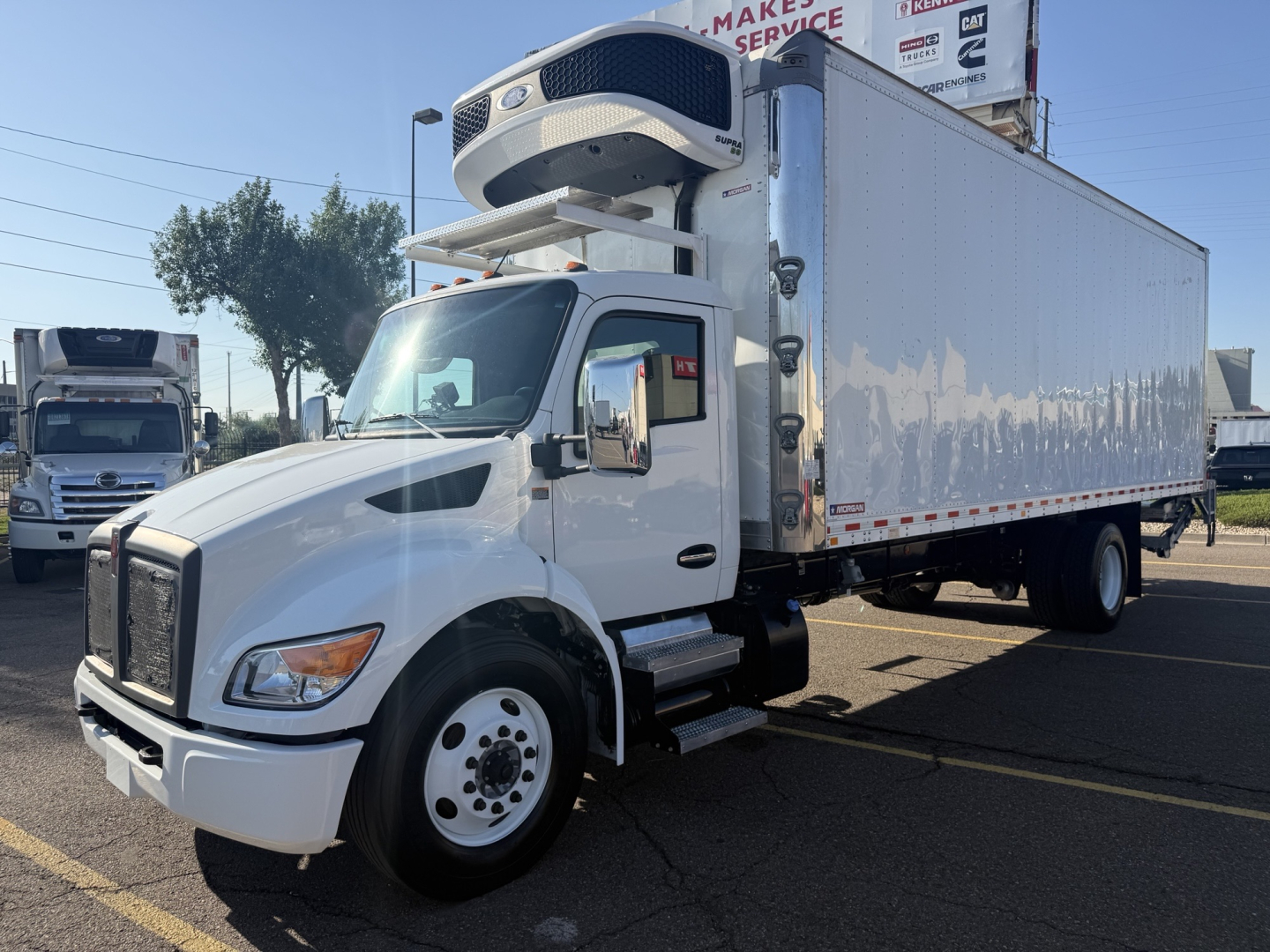Kenworth T380 refrigerated truck with carrier refrigeration unit mounted on cab, white cargo box, side mirrors, and dual rear wheels.
