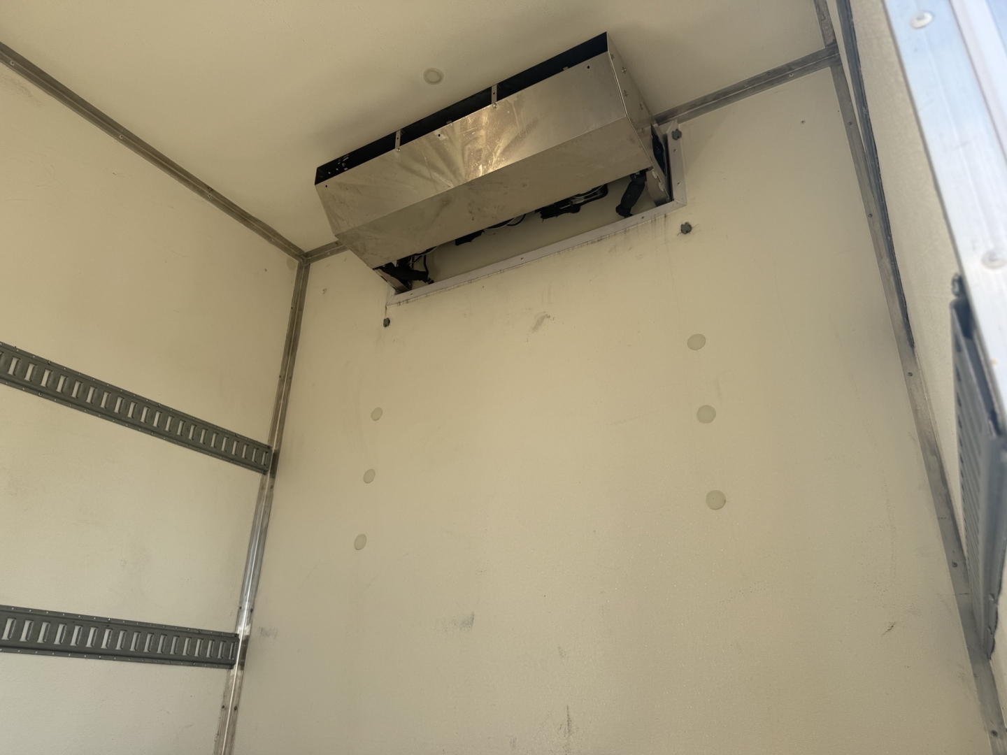 Cab interior of refrigerated Kenworth truck showing HVAC unit mounted near ceiling and insulated walls.