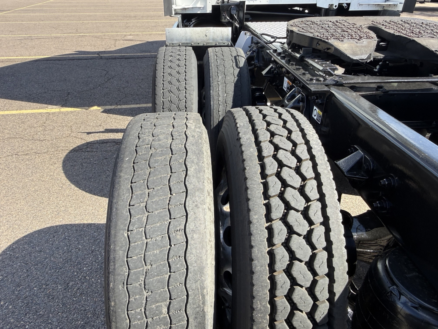 Kenworth T680 truck chassis showing rear dual tires and frame in a parking lot.