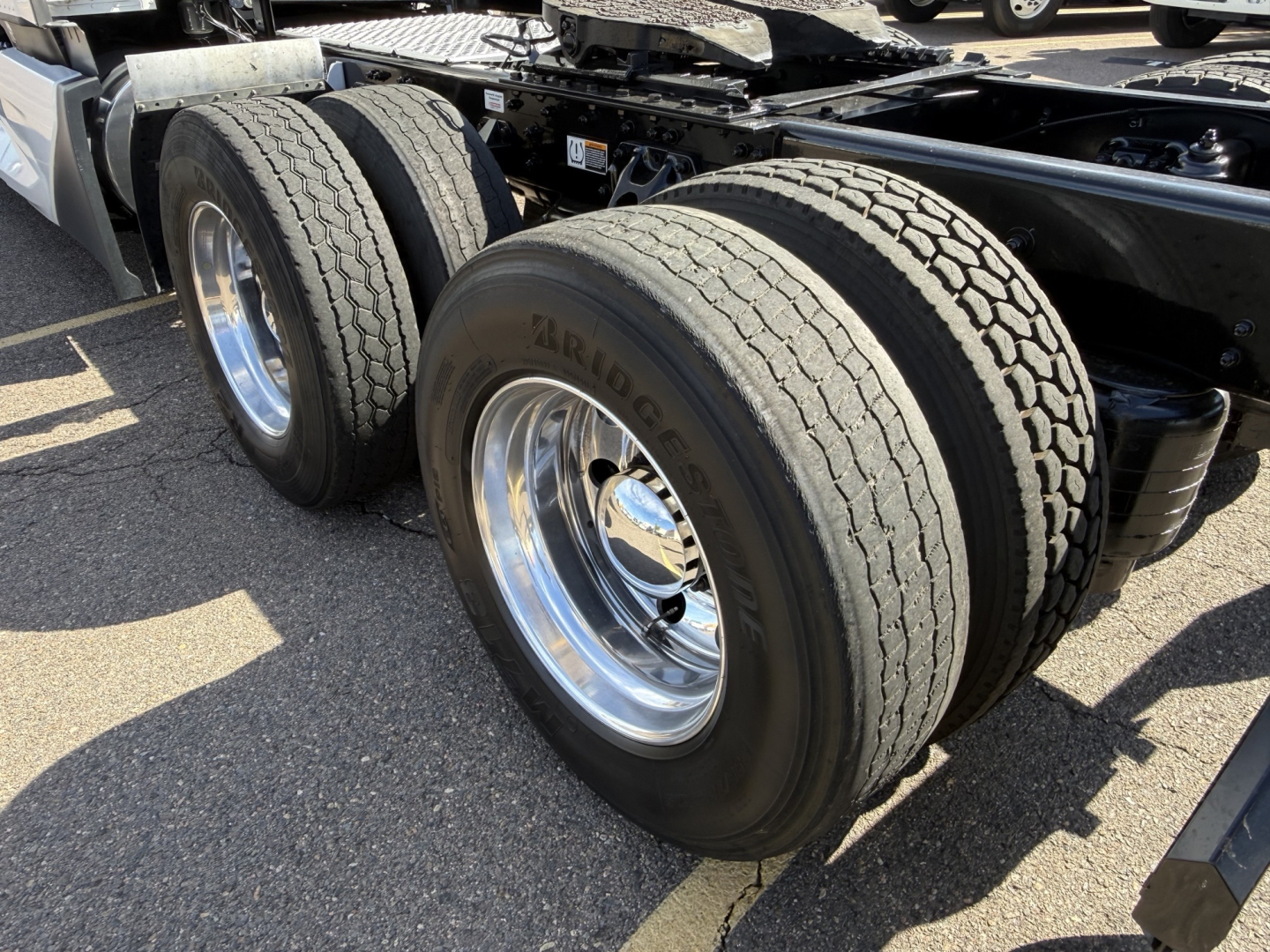 Kenworth T680 rear dual tires on tractor trailer chassis, metal rims, visible tires and lower frame rail