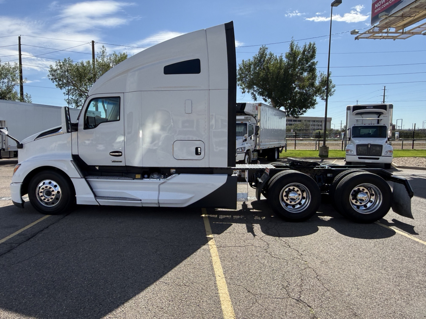 Kenworth T680 tractor in a parking lot, side view showing sleeper cab and rear dual axles
