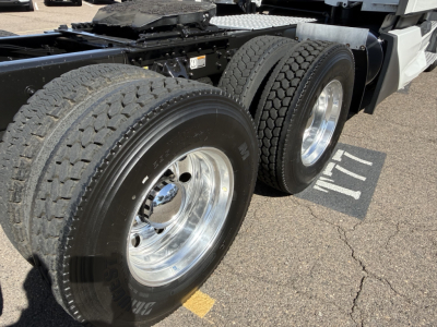 Kenworth truck tandem rear wheels and frame showing dual tire setup and polished aluminum rims.
