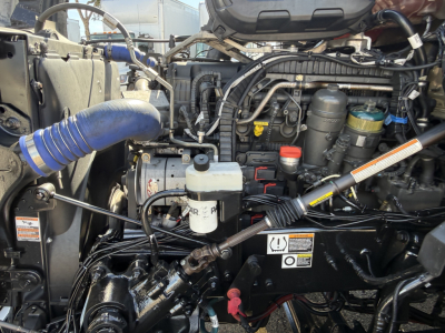 Kenworth T680 engine bay showing coolant reservoir, assorted hoses, and engine components.