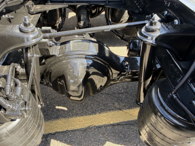 Kenworth T680 truck undercarriage showing rear axle differential, suspension components, air tanks, and dual rear wheels.