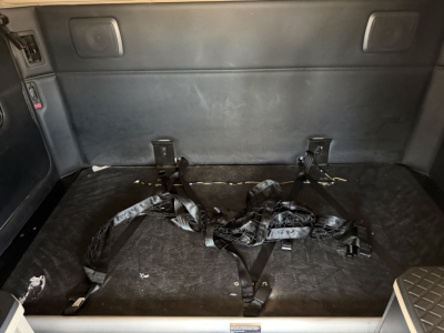 Kenworth T680 truck interior cargo area with folded seat belts and mounting brackets in rear sleeper area.