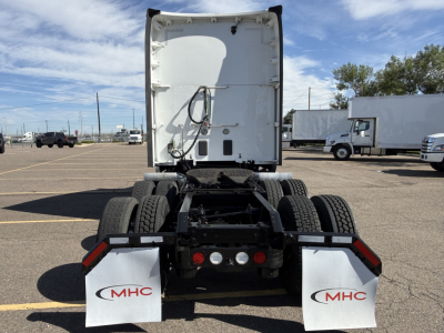 Kenworth T680 semi-truck tractor rear view showing triple-axle chassis, mud flaps with MHC logo, lights, and white sleeper cab door at the back.