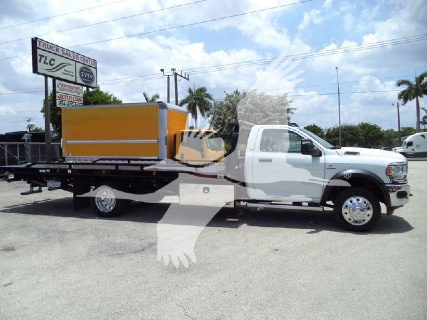 Text on the truck and signage: RAM 5500 rollback setup with a yellow equipment box on a flatbed; no legible smaller text visible.