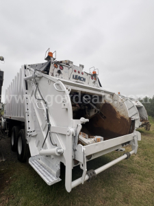 Rear view of a Sterling LT8500 refuse truck hopper with hydraulic compactor arms and warning lights.