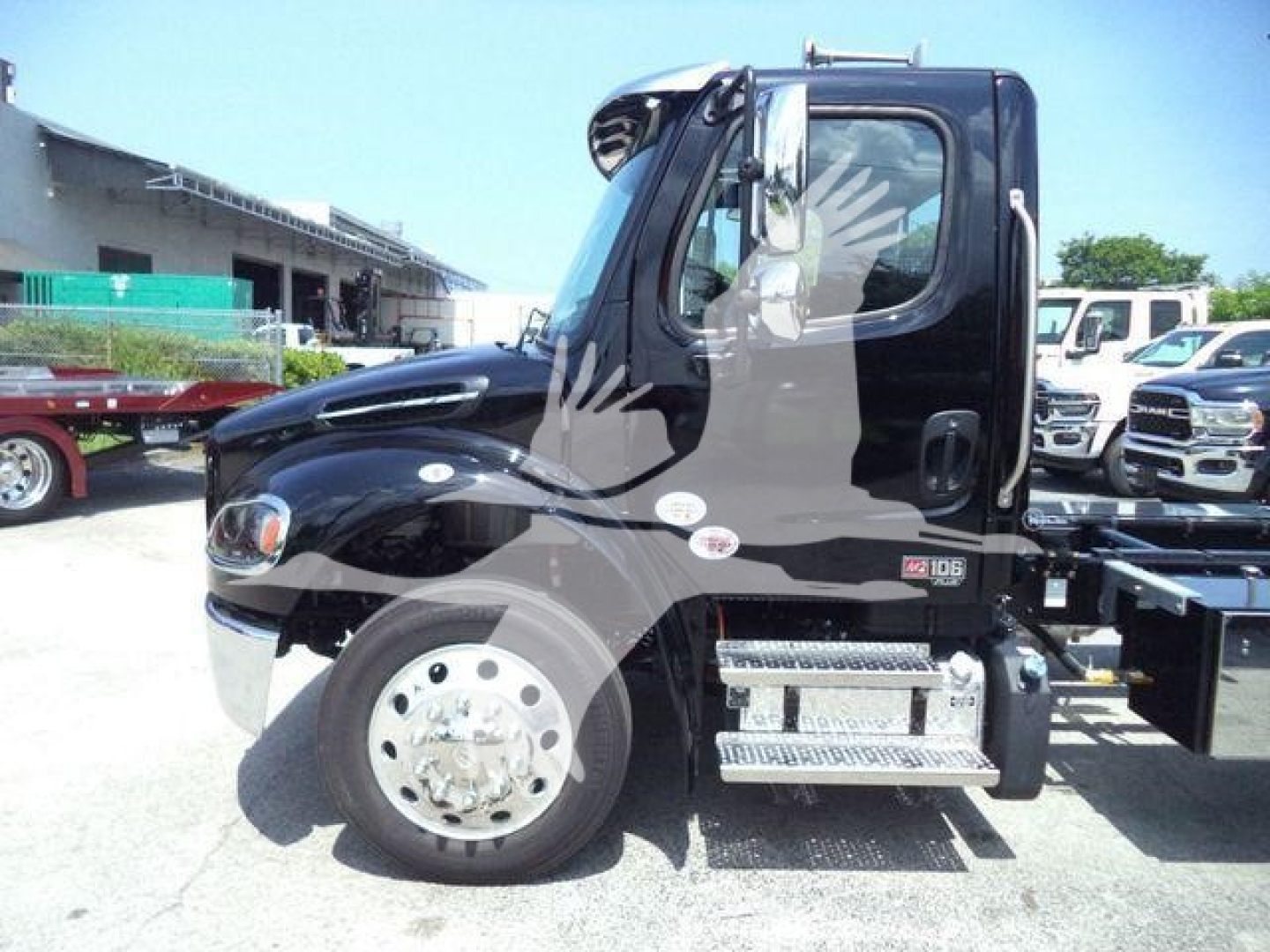 Freightliner M2 106 Plus cab with roll-back body truck, black exterior, side steps, chrome wheels. Visible text includes brand on door area and model badges.
