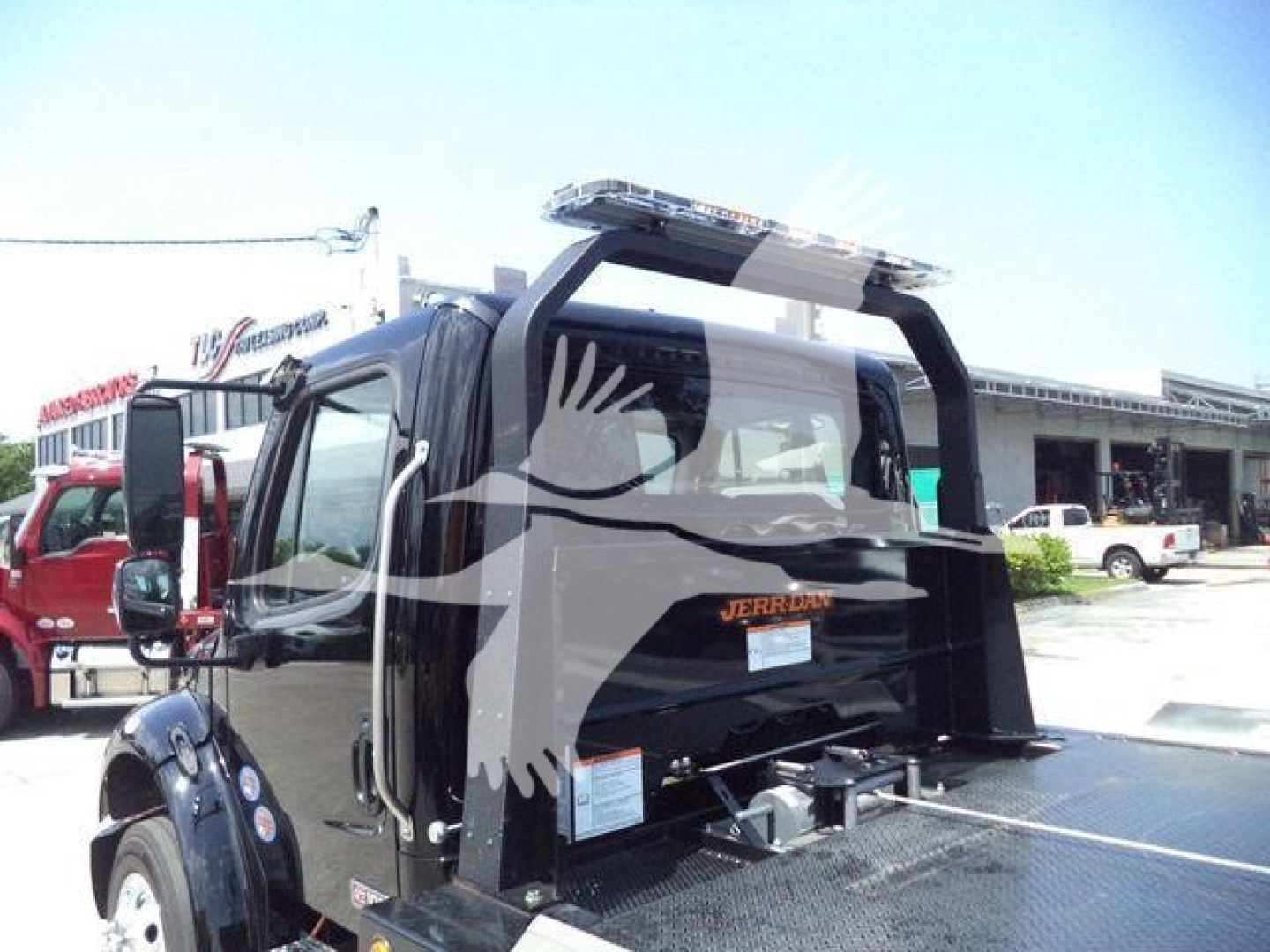 Freightliner M2 106 Plus rollback truck, rear view with loading deck and hydraulic system components visible.