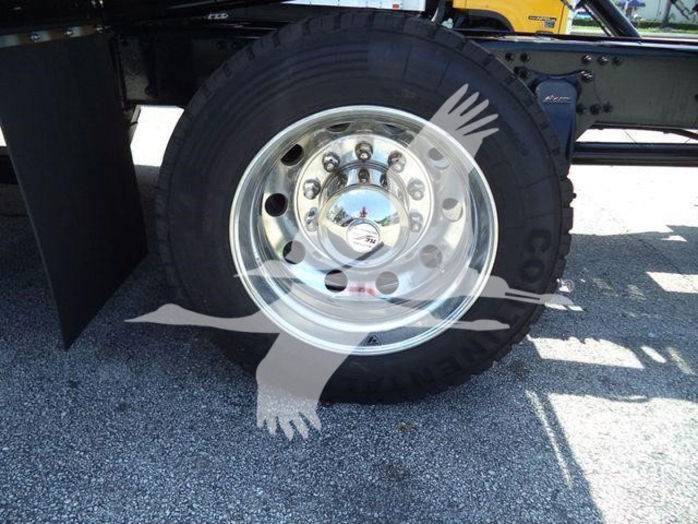 Truck wheel with chrome hub and tire, visible lug nuts and center cap; no legible text other than subtle reflections.