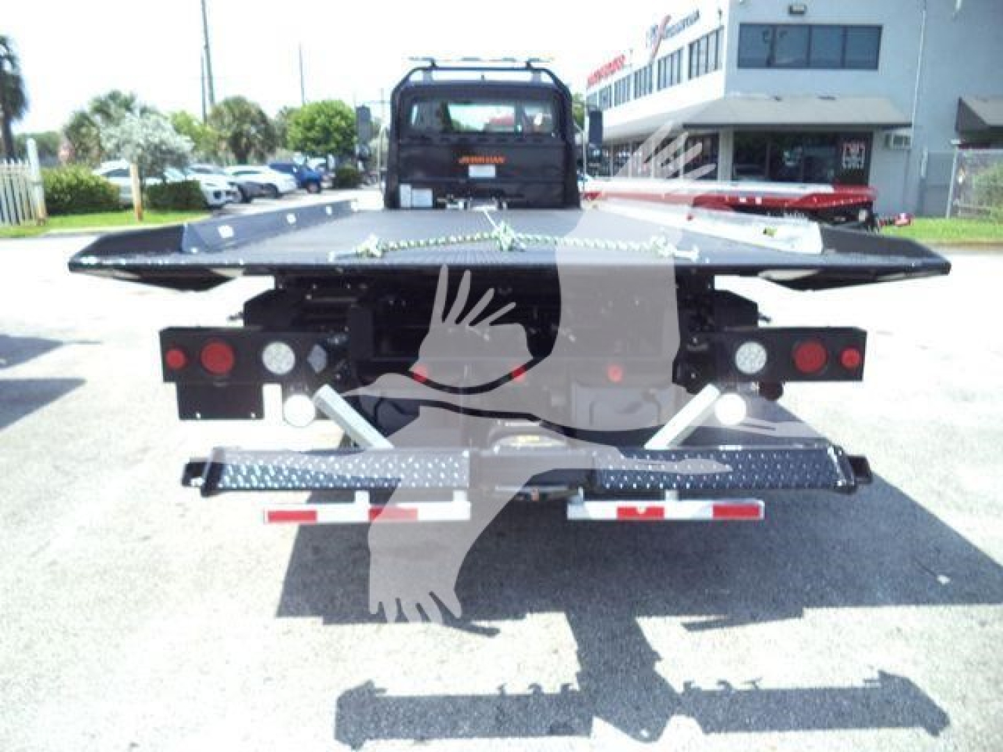 Rear view of a Freightliner rollback tow truck with a flatbed and rear lighting; no legible labels visible on the truck itself in the image.
