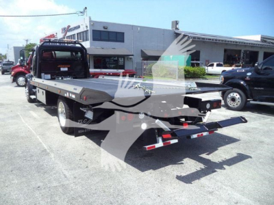 Freightliner M2 106 Plus rollback truck viewed from rear-left, shows flatbed with towing equipment and rear lights.