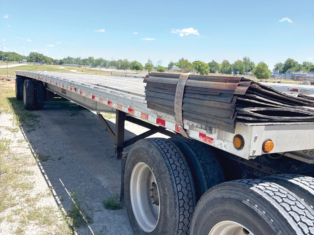 Trailer side view showing Chaparral aluminum flatbed with stacked metal decking on the bed and dual rear axles.