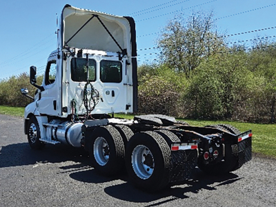 Truck chassis of a 2019 Freightliner Cascadia126 daycab showing rear dual-axle configuration and exposed engine bay with cab raised.