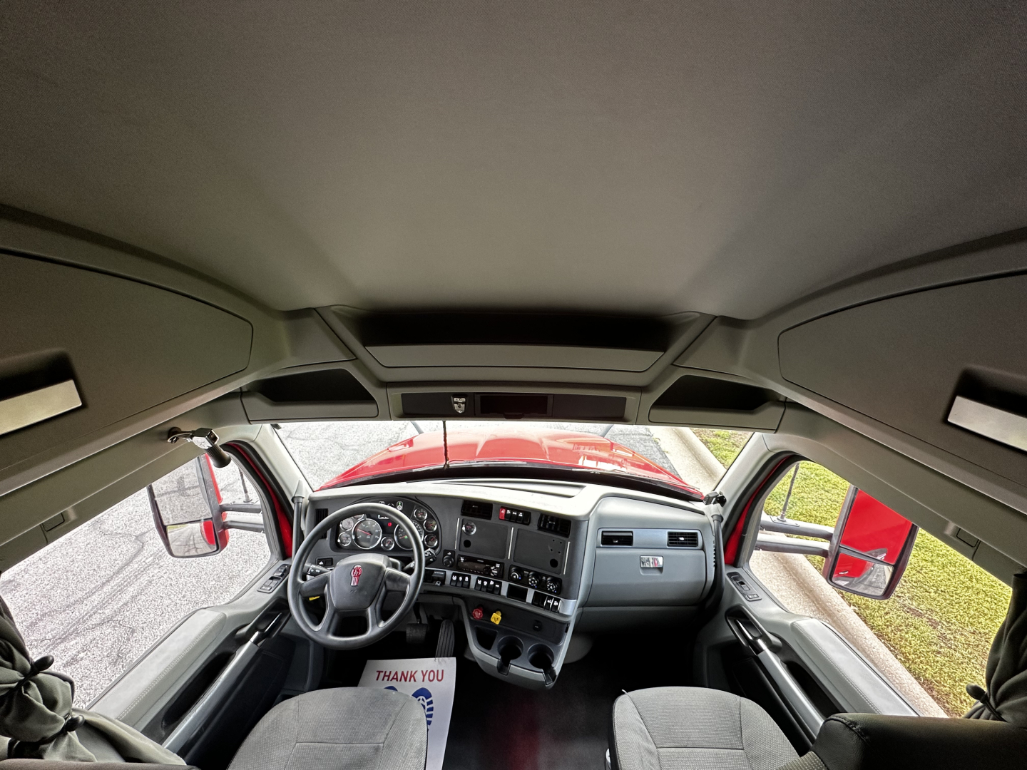 Interior of a 2022 Kenworth T680 cab view from driver's seat showing steering wheel and dashboard panels.