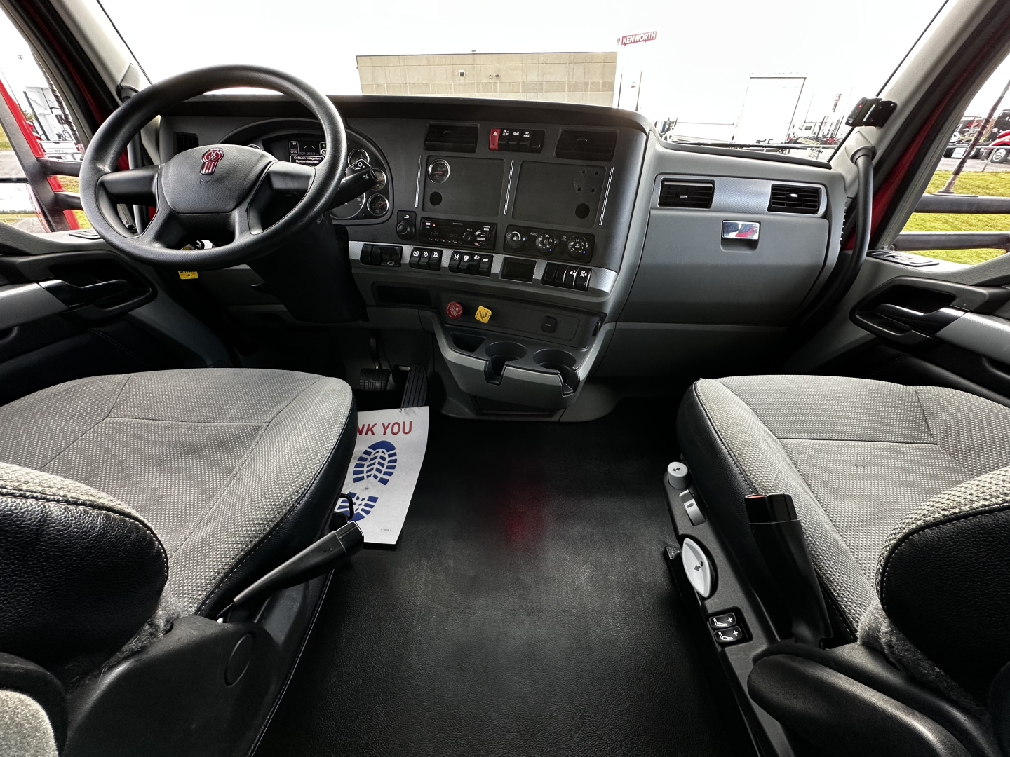 Kenworth T680 truck interior dashboard and front seats with steering wheel and controls visible.