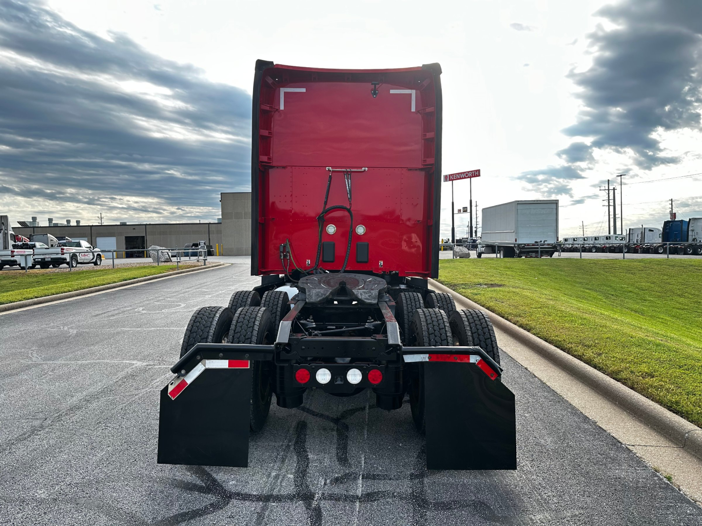 Kenworth T680 rear view showing fifth wheel, rear tires, and mud flaps in a truck yard.