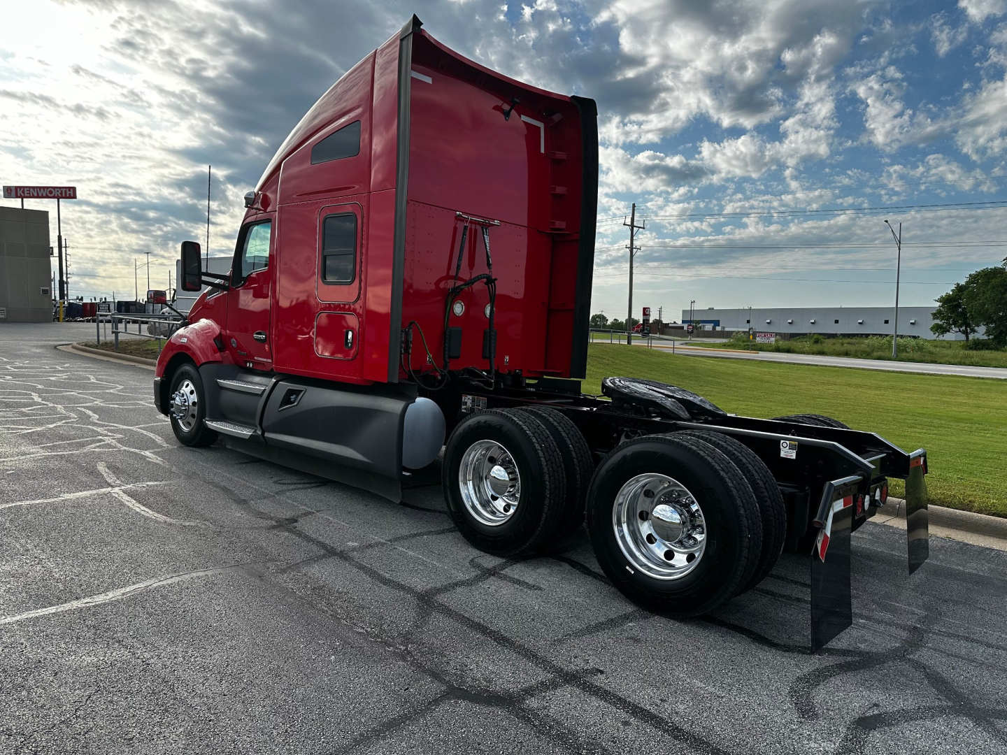 Kenworth T680 tractor in red, side view showing sleeper cab, dual rear axles, chrome wheels, chassis, and rear underride area.