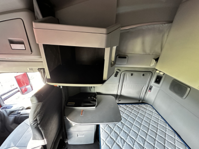 Kenworth T680 sleeper cab interior showing upper storage cabinet and fold-out desk/table in a compact bunk area.