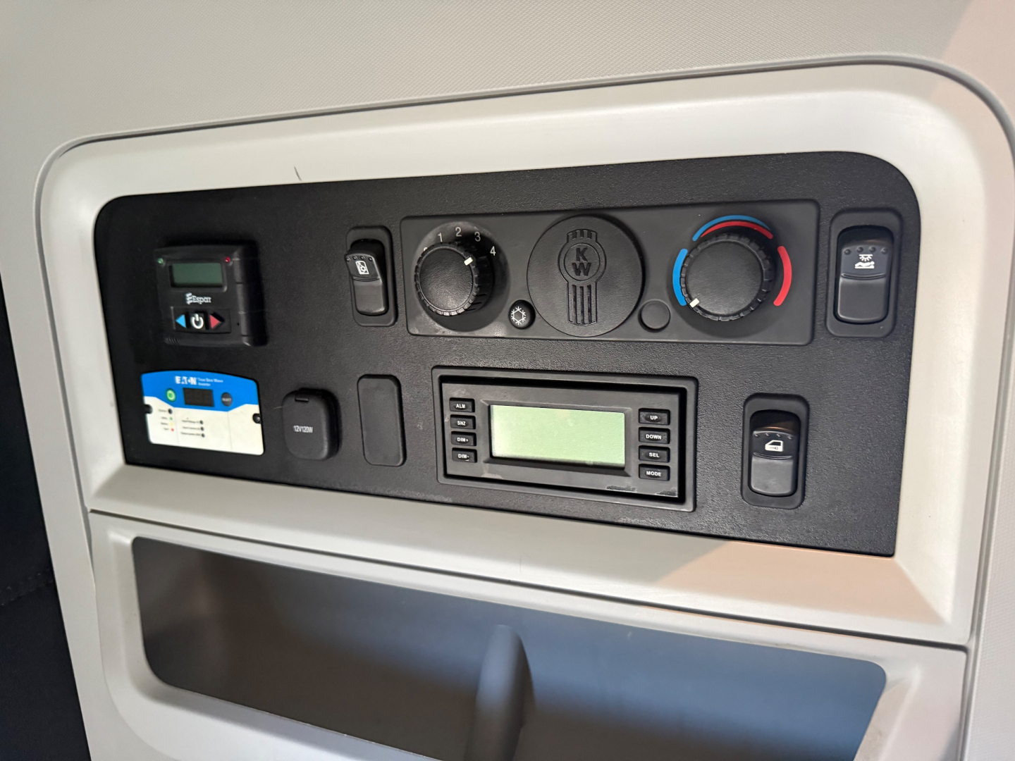 Dashboard control panel of a Kenworth truck showing climate controls, radio, and various switches.
