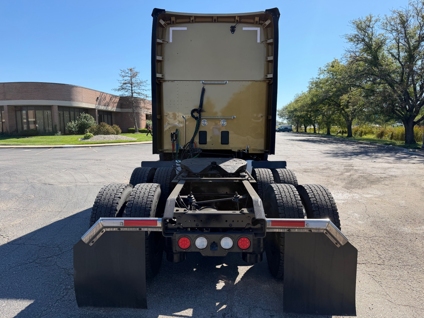 Kenworth T680 rear view showing fifth wheel area and dual rear axles with mud flaps and LED taillights.