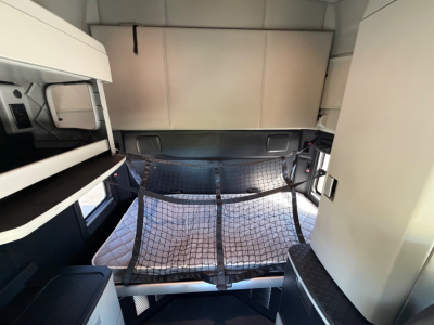 Kenworth T680 sleeper cab interior view showing cargo net and storage shelves.