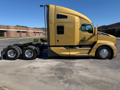 Kenworth T680 tractor side profile in tan color showing sleeper cab and dual rear axles.