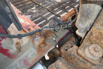Truck cab frame showing rusted chassis area with wiring harnesses and metal brackets in a Mack CHN613 engine bay vin tag not visible.