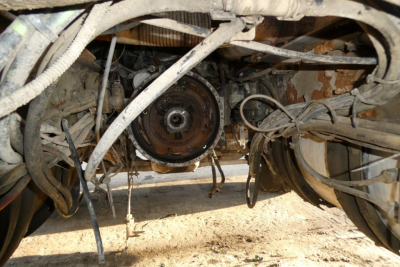 Rear view of a 2005 Mack CHN613 chassis showing exposed driveline with circular clutch/ flywheel area and wiring harnesses beneath the cab.
