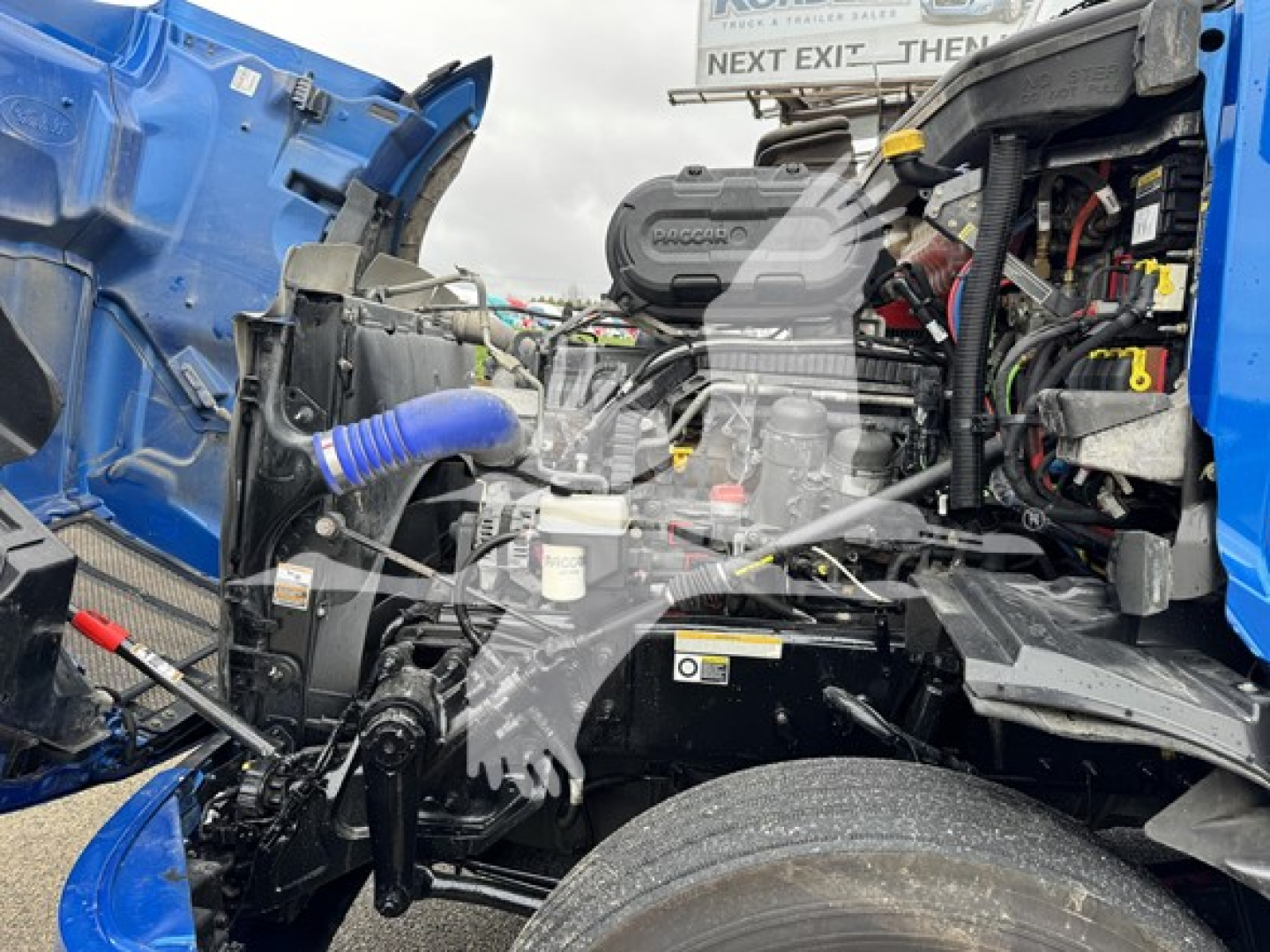 Vehicle engine bay of a 2023 Peterbilt 579 conventional sleeper showing engine components and hood open.