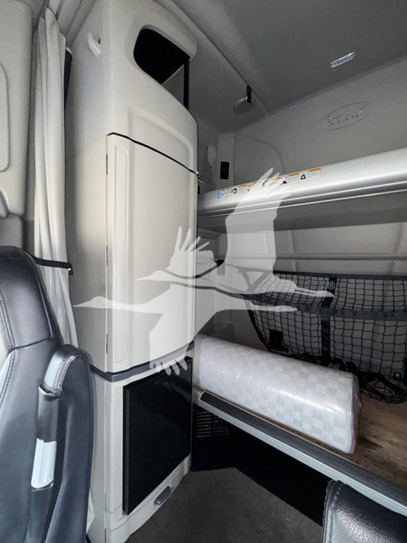 Peterbilt 579 sleeper cab interior showing vertical cabinet, bunk bed area, and storage nets in cabin.