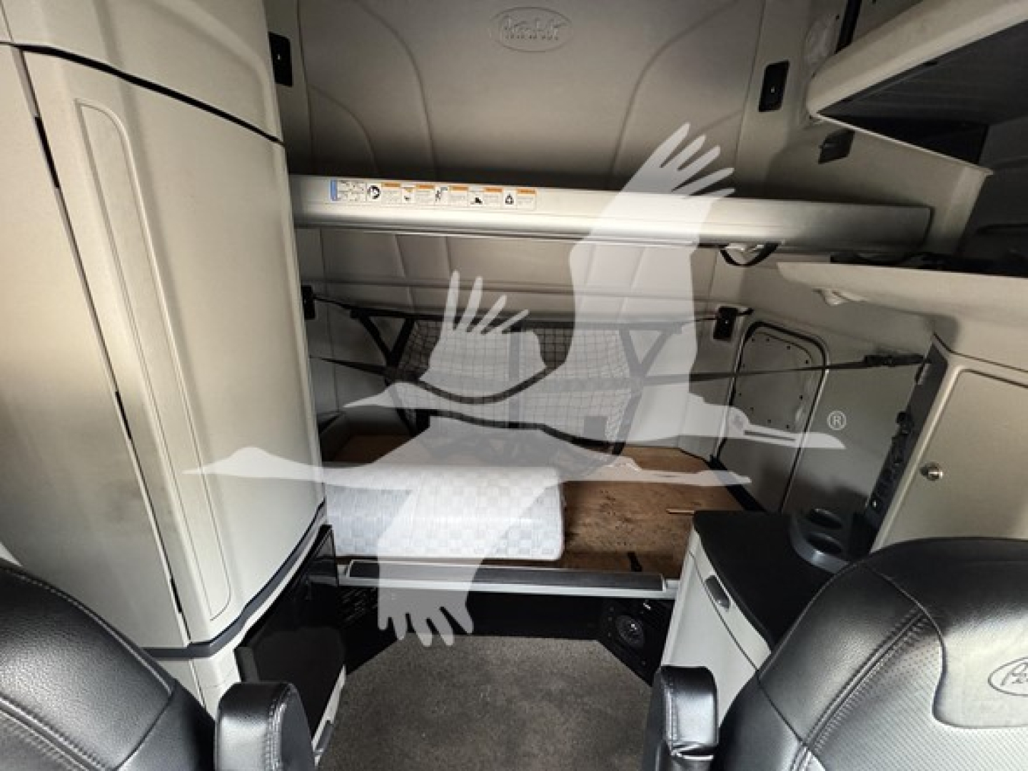 Peterbilt 579 cab interior showing under-bunk storage area and sleeper berth in-view with label panel and metal supports.