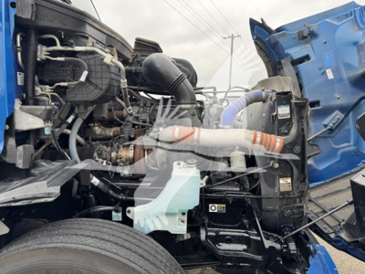 Peterbilt 579 engine bay showing coolant reservoir and various hoses and components under open hood.
