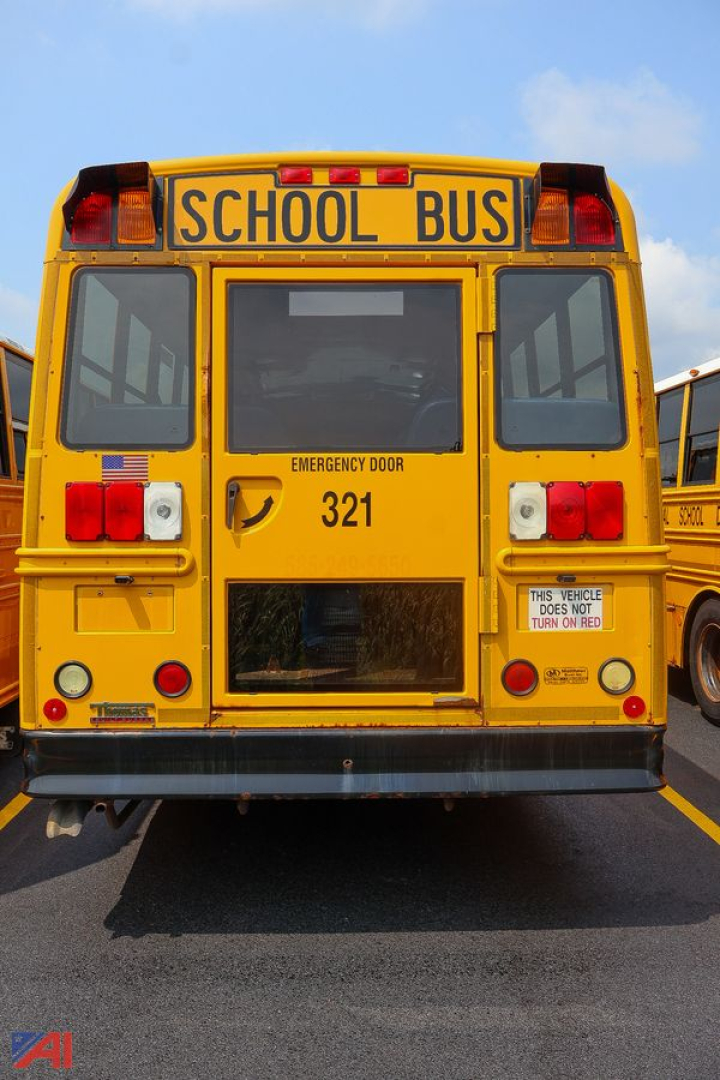 School bus rear view showing 321 fleet number, Emergency Door label, and 'SCHOOL BUS' sign on top.