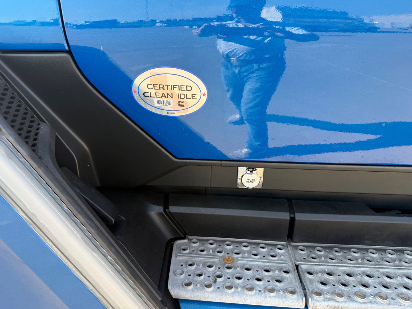 Kenworth T680 side step area with Certified Clean Idle sticker on blue door panel and metal running board.