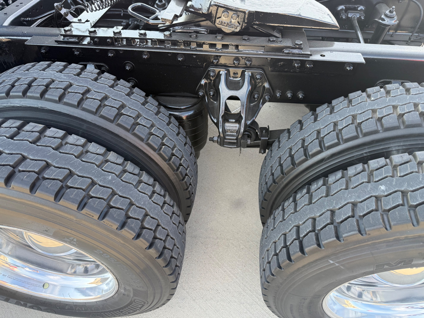 Kenworth T680 undercarriage showing twin rear axles with heavy-duty dual tires and suspension components.