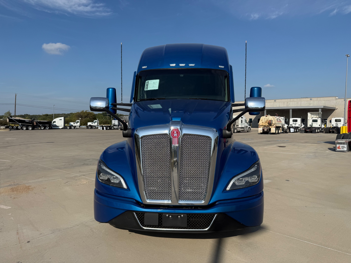 Kenworth T680 front view showing blue cab and chrome grille with large hood emblem.