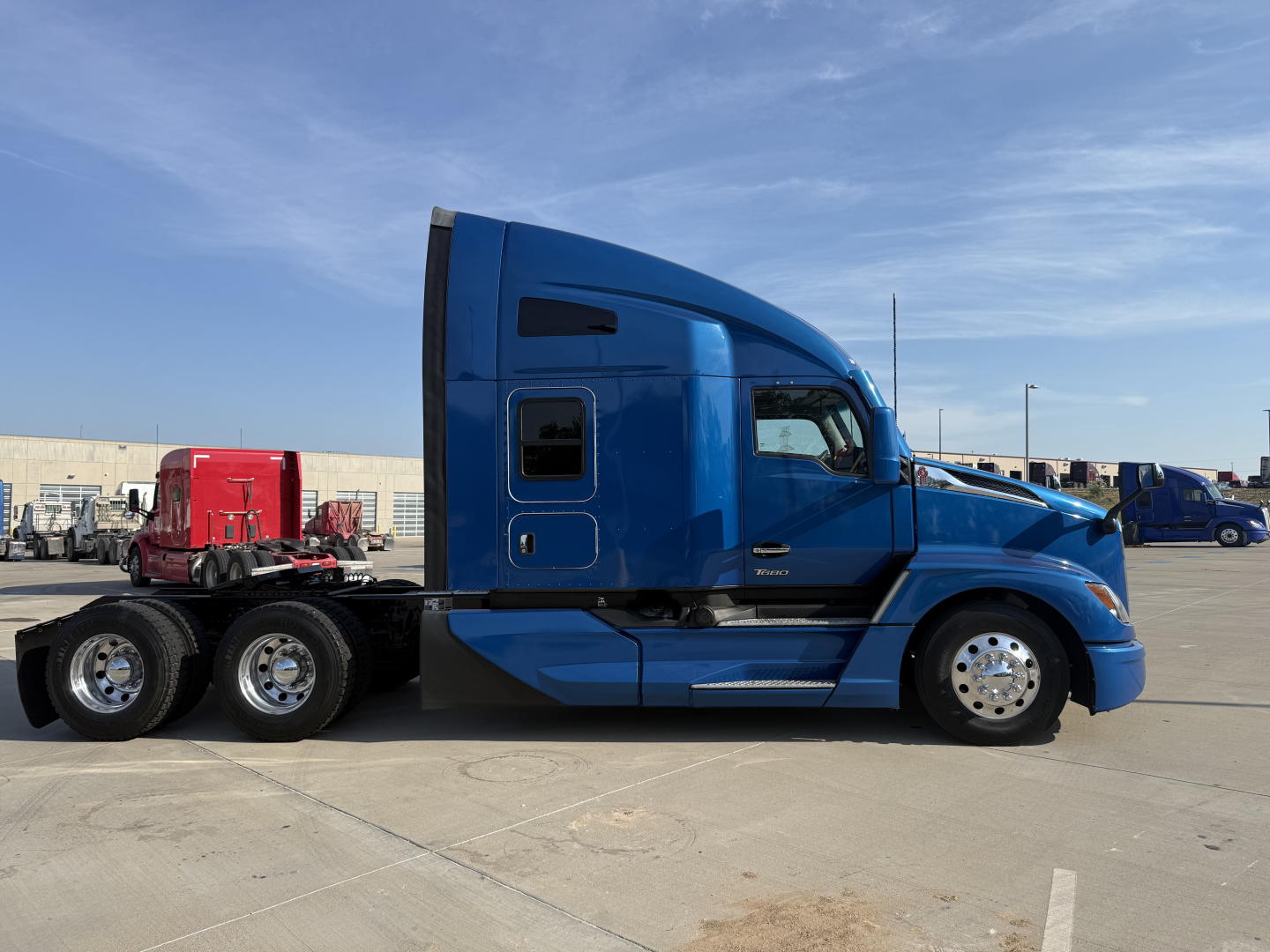 Kenworth T680 sleeper cab truck side view showing blue exterior and rear chassis with dual rear axles.