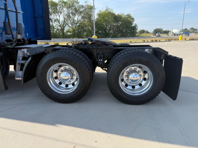 Kenworth T680 rear dual-axle wheels with chrome hubcaps and mud flaps, chassis frame and tires visible.