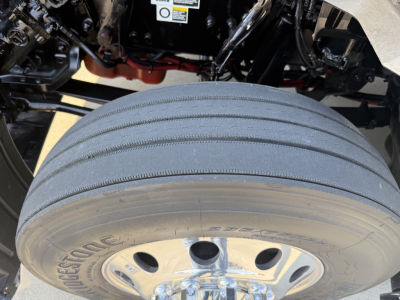 Kenworth T680 wheel/tire close-up showing duals and rear underside components with visible truck frame.