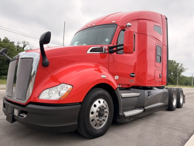 Kenworth T680 conventional sleeper truck in red, front-left view showing hood, grille, headlights, and side steps.