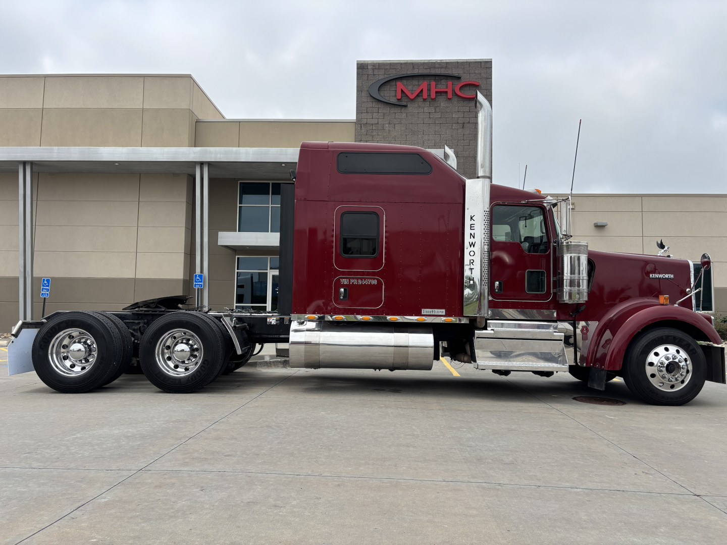 Kenworth W900L tractor-trailer cab side profile view showing burgundy cab and chrome fuel tanks.