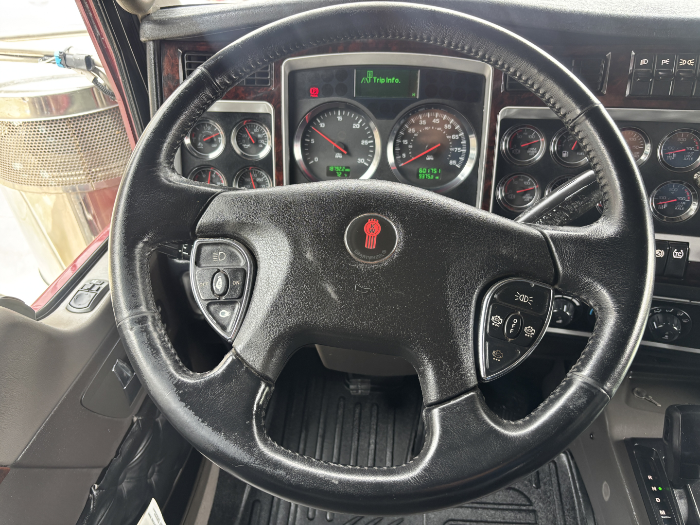 Kenworth W900L truck interior steering wheel and instrument cluster with gauges and controls visible.