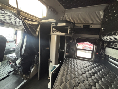 Kenworth W900L sleeper cab interior showing bunk area with quilted upholstery and storage compartments.
