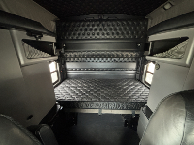 Interior sleeper cab cargo area of a 2023 Kenworth W900L showing a quilted bed mattress and padded walls.