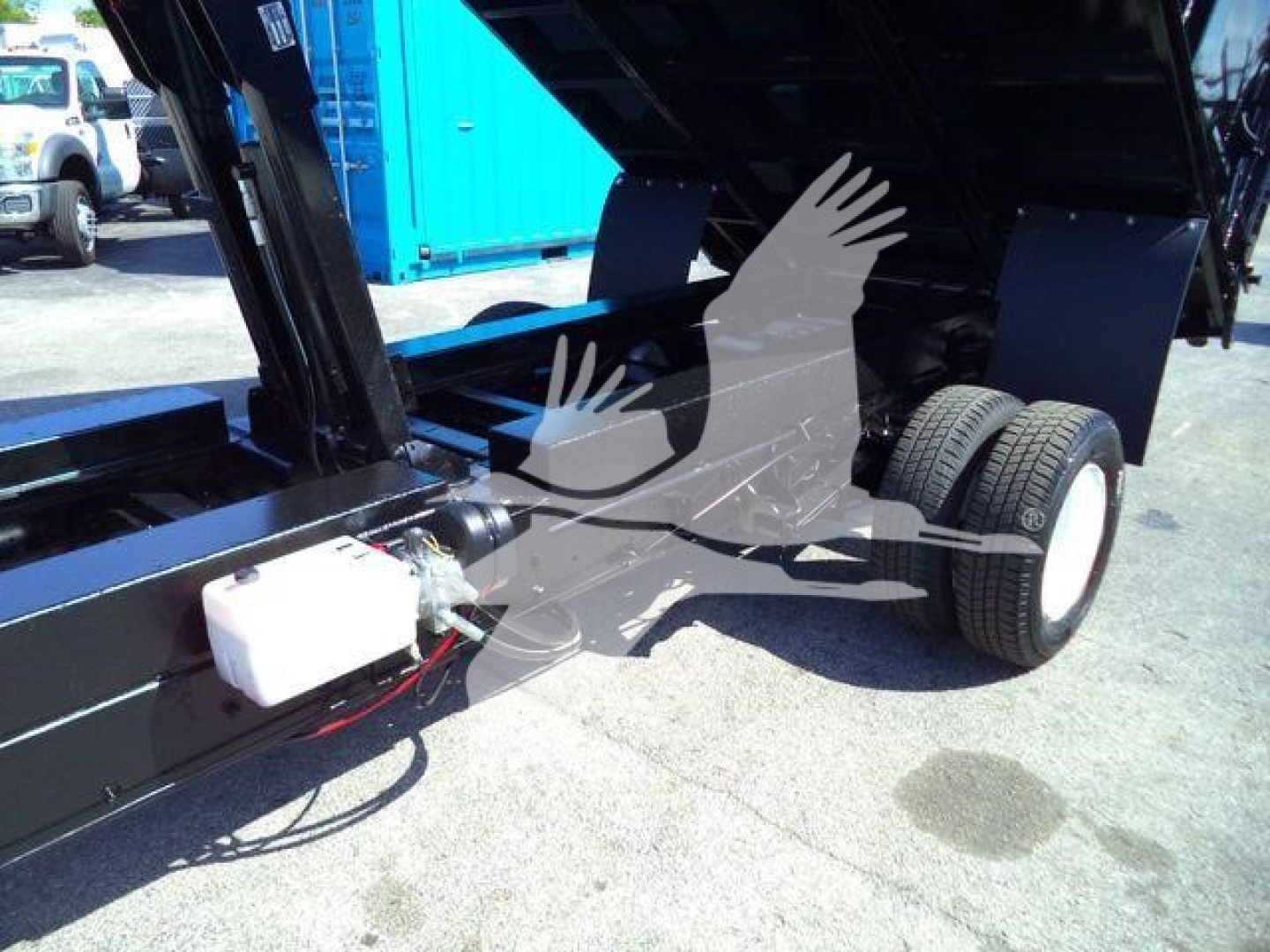 Truck bed of a 2011 Ford E450 dump truck showing hydraulic system and white reservoir with hoses.