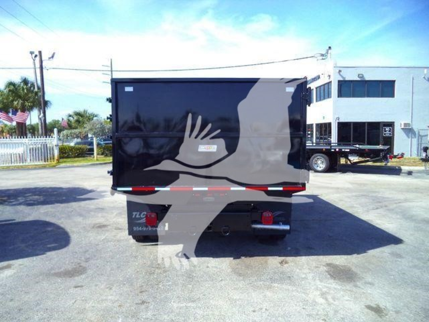 Truck dump bed rear view showing tail lights and bumper with black box body in a parking lot.